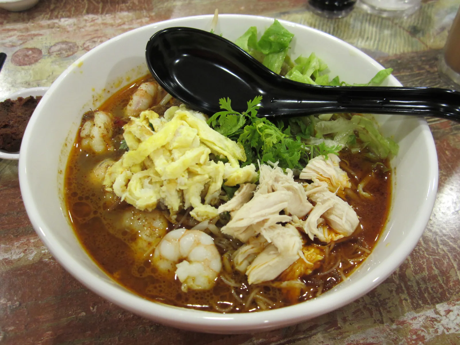 Laksa Sarawak dengan udang, mie, dan potongan telur dadar